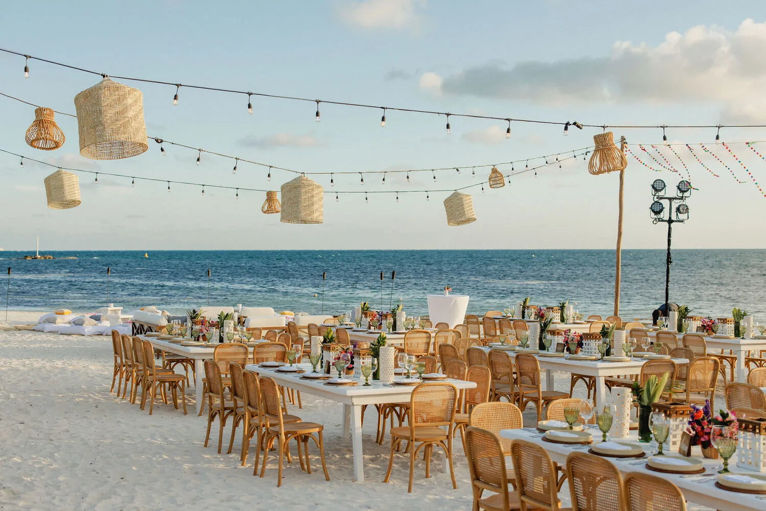 Beach wedding reception at NIZUC Resort & Spa in Cancun. Tables with rattan chairs face the ocean.