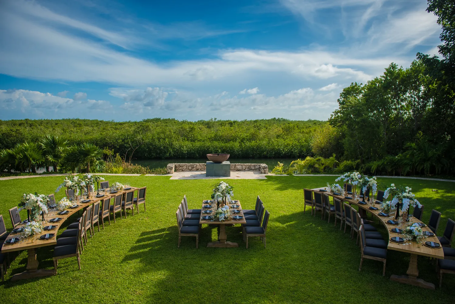 Elegant outdoor wedding reception at NIZUC Resort & Spa in Cancun, featuring long wooden tables with floral centerpieces.