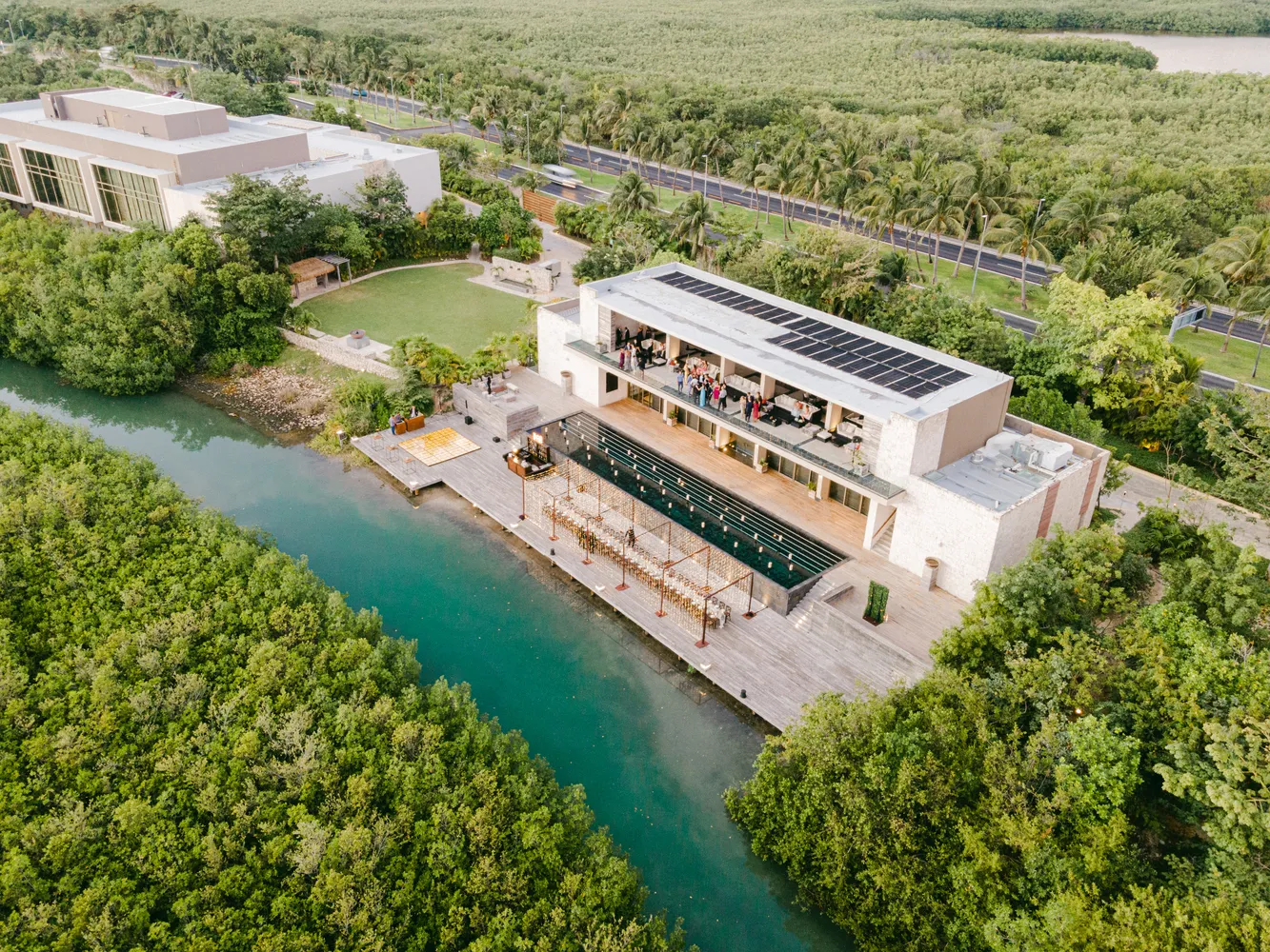 Aerial view of a Cancun wedding reception at NIZUC Resort & Spa. Guests gather on a patio overlooking a pool and lagoon.