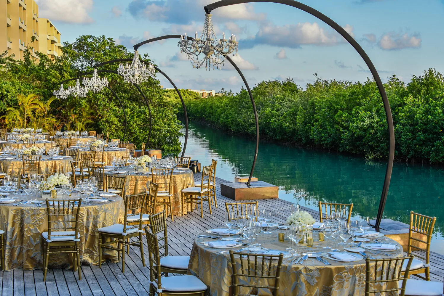 Elegant Cancun wedding reception at NIZUC Resort & Spa, featuring gold linens and crystal chandeliers.