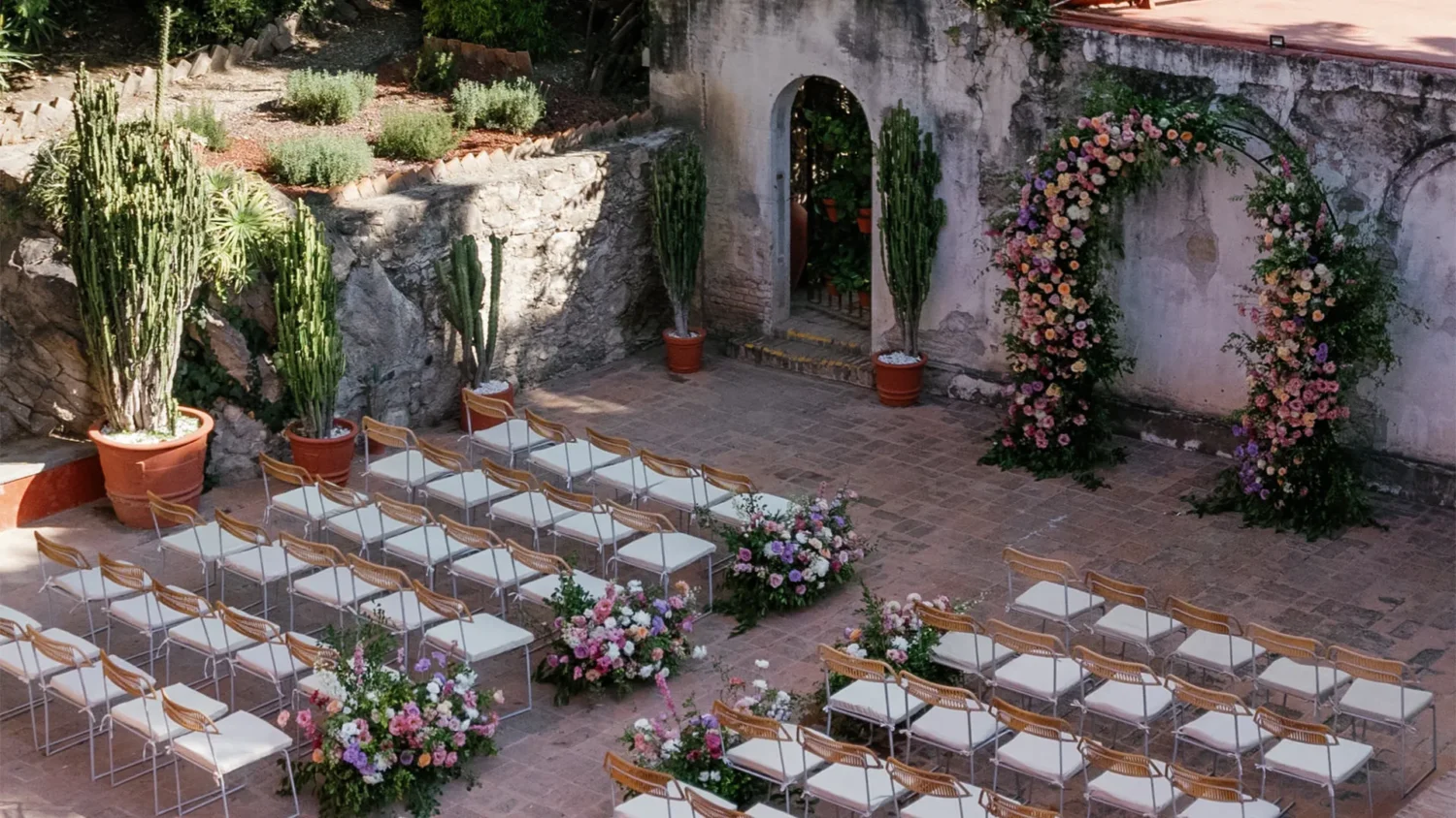 Outdoor wedding ceremony setup at Casa de Sierra Nevada, featuring floral arch and rows of chairs.