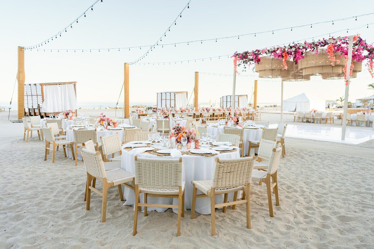 Los Cabos destination wedding reception on the beach with round tables and string lights.