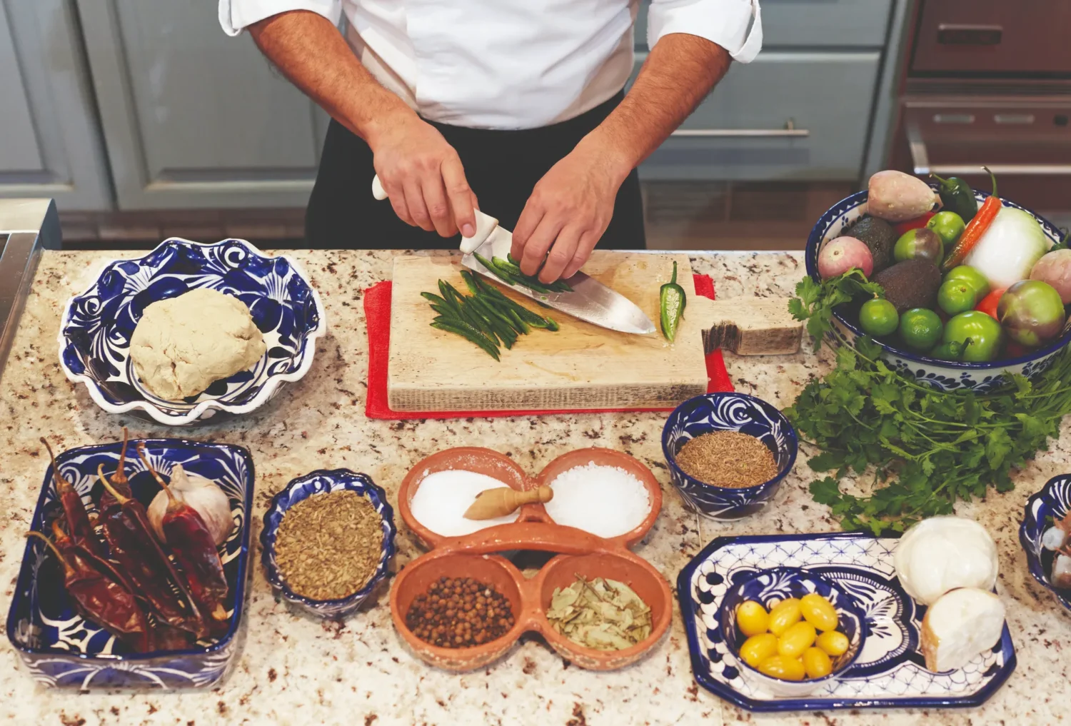 Chef preparing ingredients for a Mexican dish. Various spices and vegetables are visible.