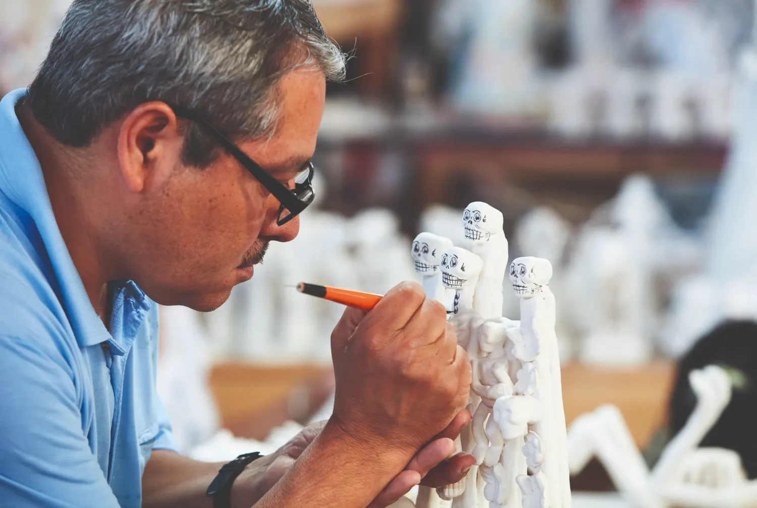 Artisan hand-painting Calavera details on a Day of the Dead sculpture.
