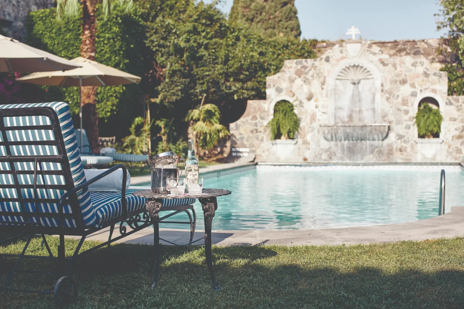 Relaxing poolside at Casa de Sierra Nevada, Belmond Hotel, with drinks and a view of a stone fountain.