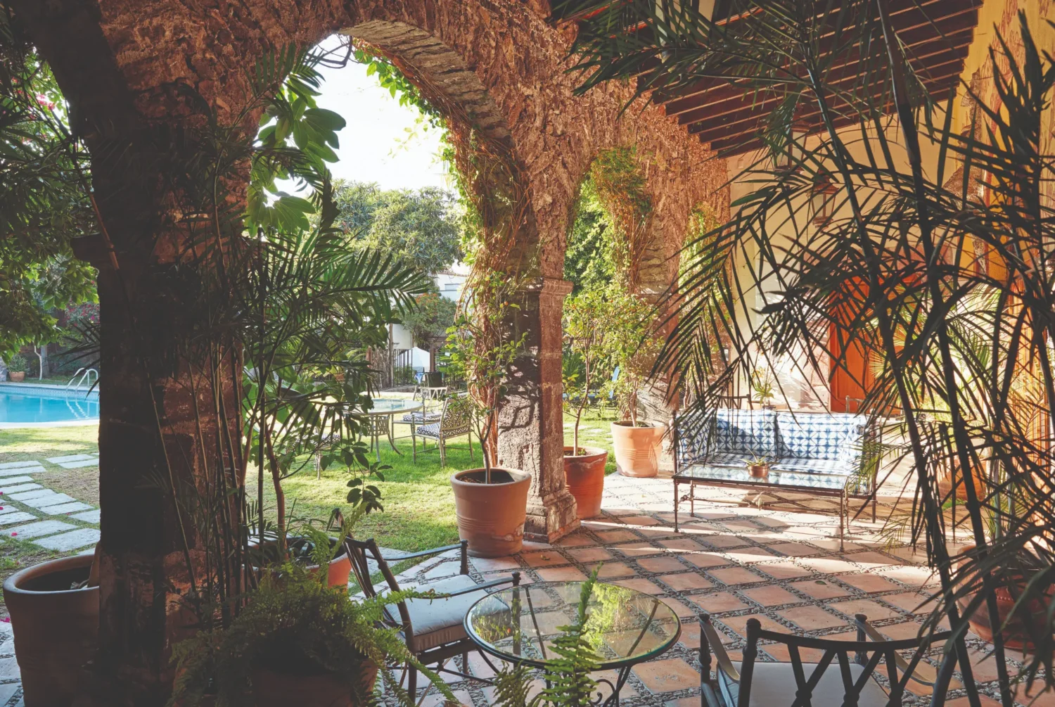 Peaceful courtyard at Casa de Sierra Nevada, Belmond Hotel, San Miguel de Allende. Lush greenery surrounds a seating area.
