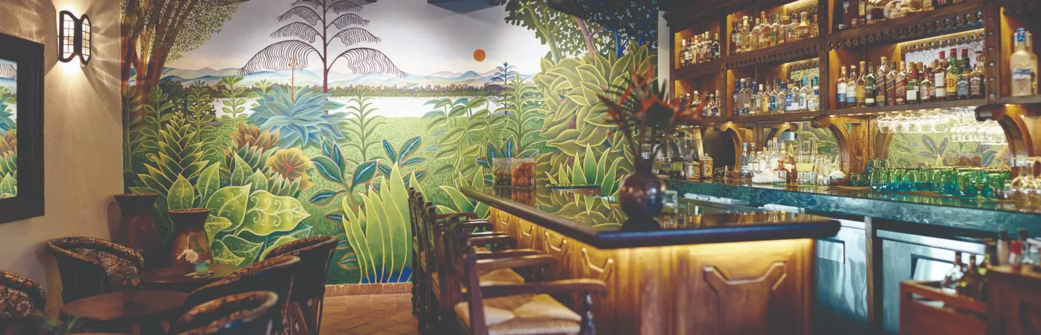 Luxurious bar at Casa de Sierra Nevada, Belmond Hotel, San Miguel de Allende. Lush tropical mural backdrop.