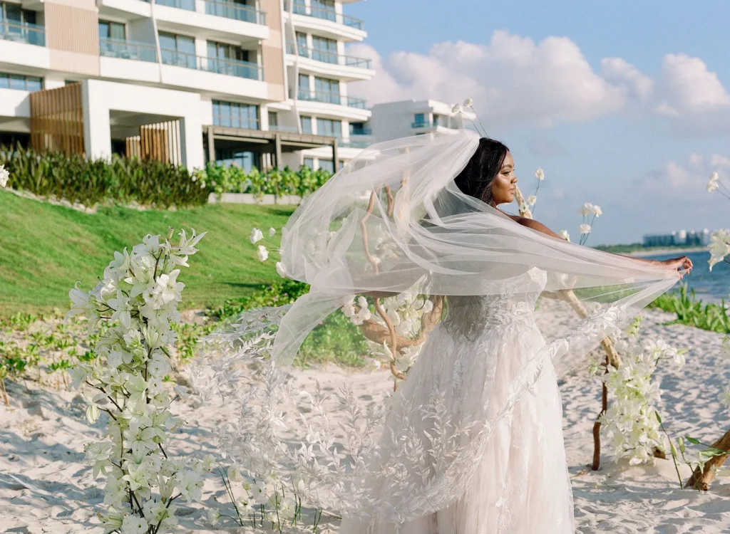 Bride in flowing wedding dress and veil on a beach, luxury destination wedding at Waldorf Astoria Riviera Maya.