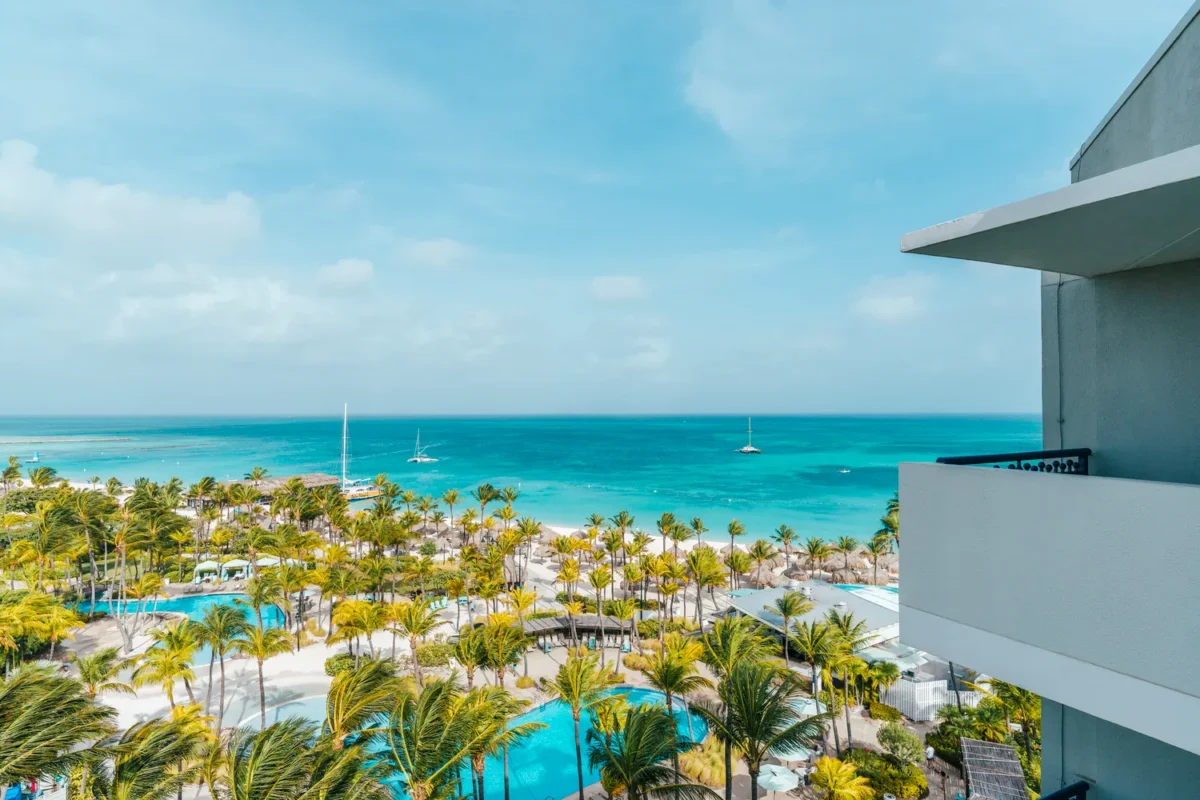 Aerial view of Hilton Aruba Caribbean Resort with turquoise water, beach, and palm trees. Perfect for a Hilton Aruba Destination Wedding.