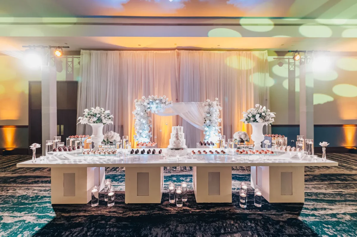Elegant dessert table at a Hilton Aruba Destination Wedding with floral arch and cake