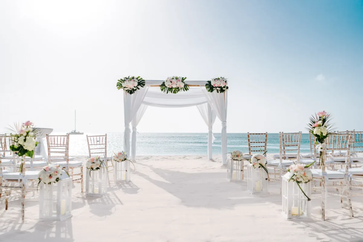 Beach wedding setup at Hilton Aruba Caribbean Resort. Destination wedding with flowers, chairs, and arch.