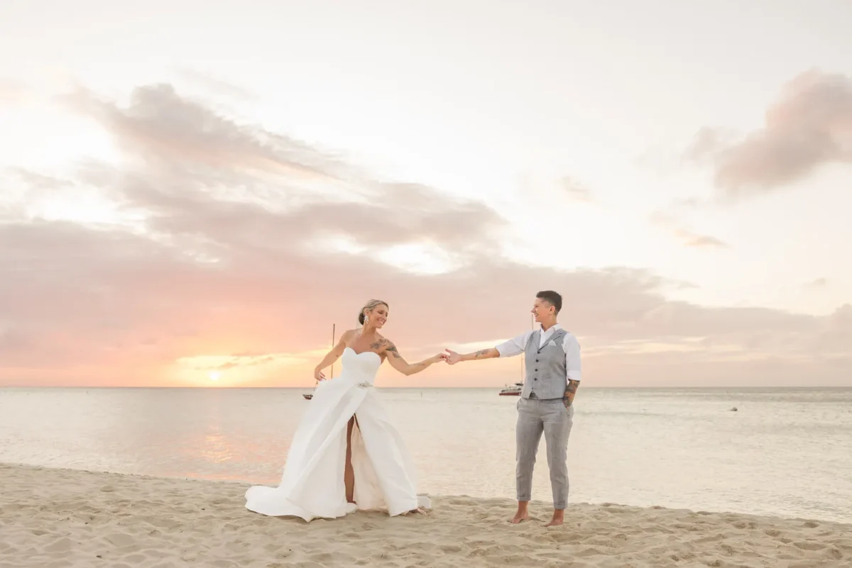 Couple holding hands on a beach at sunset for their Hilton Aruba Destination Wedding.