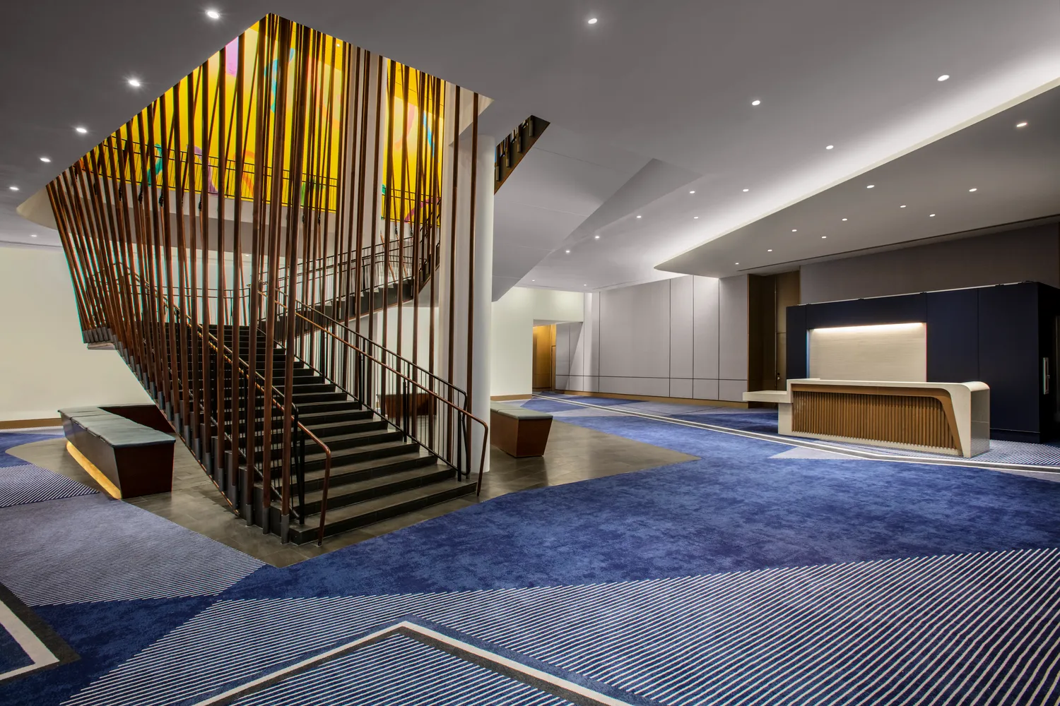Modern NYC wedding venue: elegant lobby with staircase and reception desk at Conrad New York Downtown.
