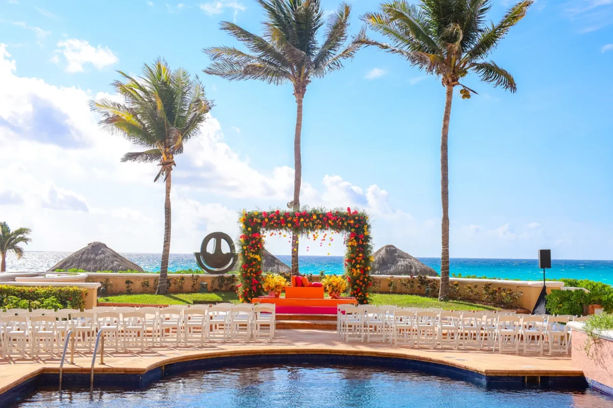 Destination Wedding Resort: Outdoor wedding setup with floral arch, chairs, and ocean view at Kempinski Hotel Cancún.