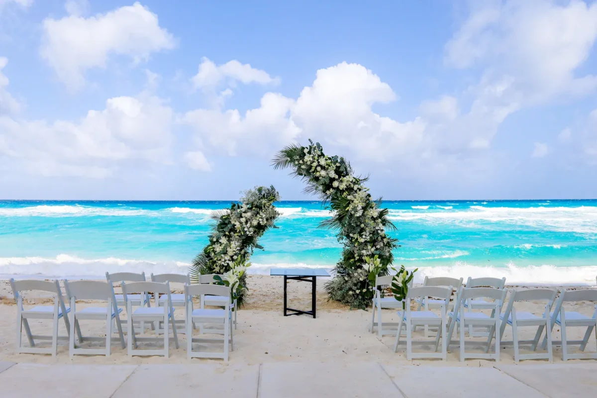 Beach destination wedding resort setup at Kempinski Hotel Cancún with floral arch and ocean view.