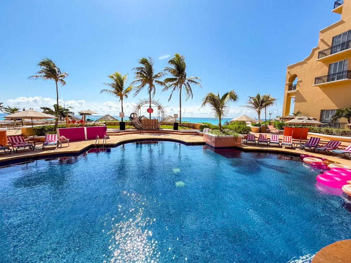 Luxury pool at Kempinski Hotel Cancún, a Destination Wedding Resort, with palm trees and ocean view.