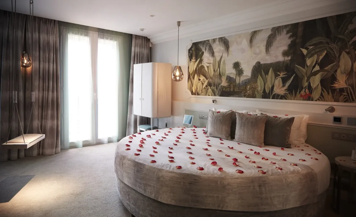 Romantic Paris hotel room with circular bed, rose petals, and tropical wall art. Perfect for a honeymoon.