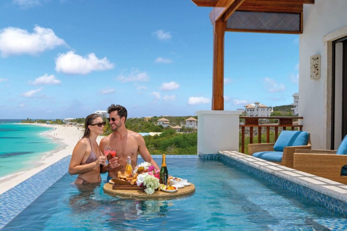 Couple enjoying champagne and cocktails in a private pool overlooking Anguilla beach. Luxury destination wedding at Zemi Beach House.