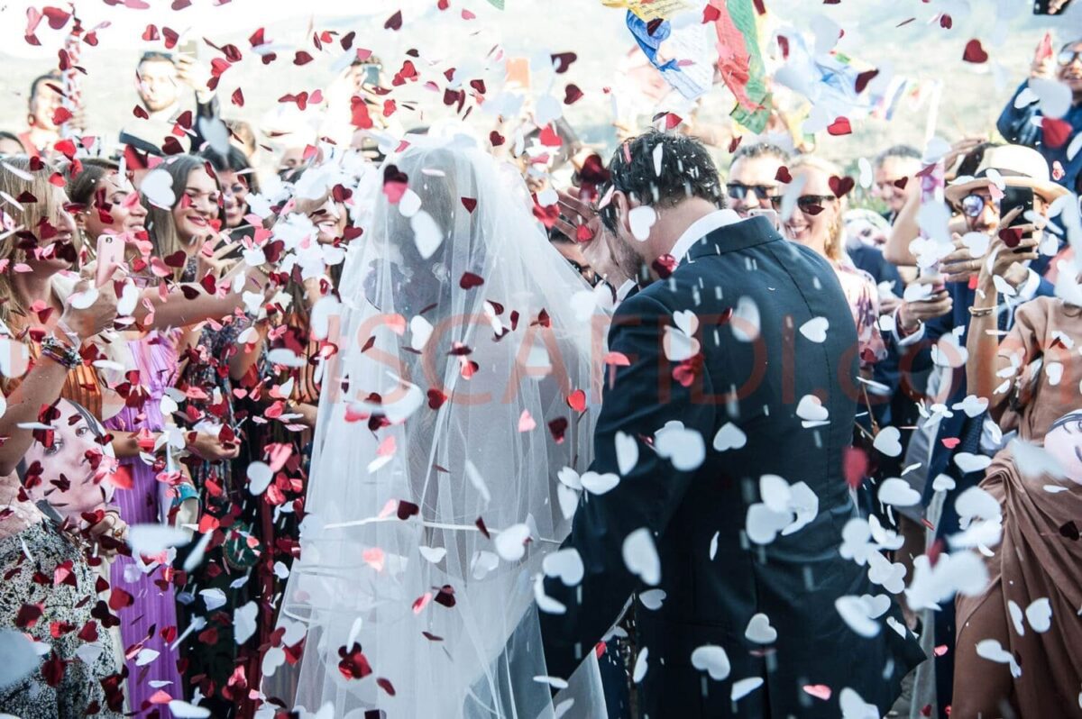Bride and groom surrounded by guests throwing rose petals at a Spanish wedding