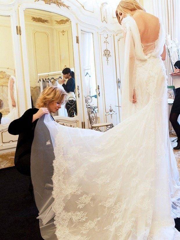 Bride trying on a lace wedding gown, assisted by a stylist in a boutique