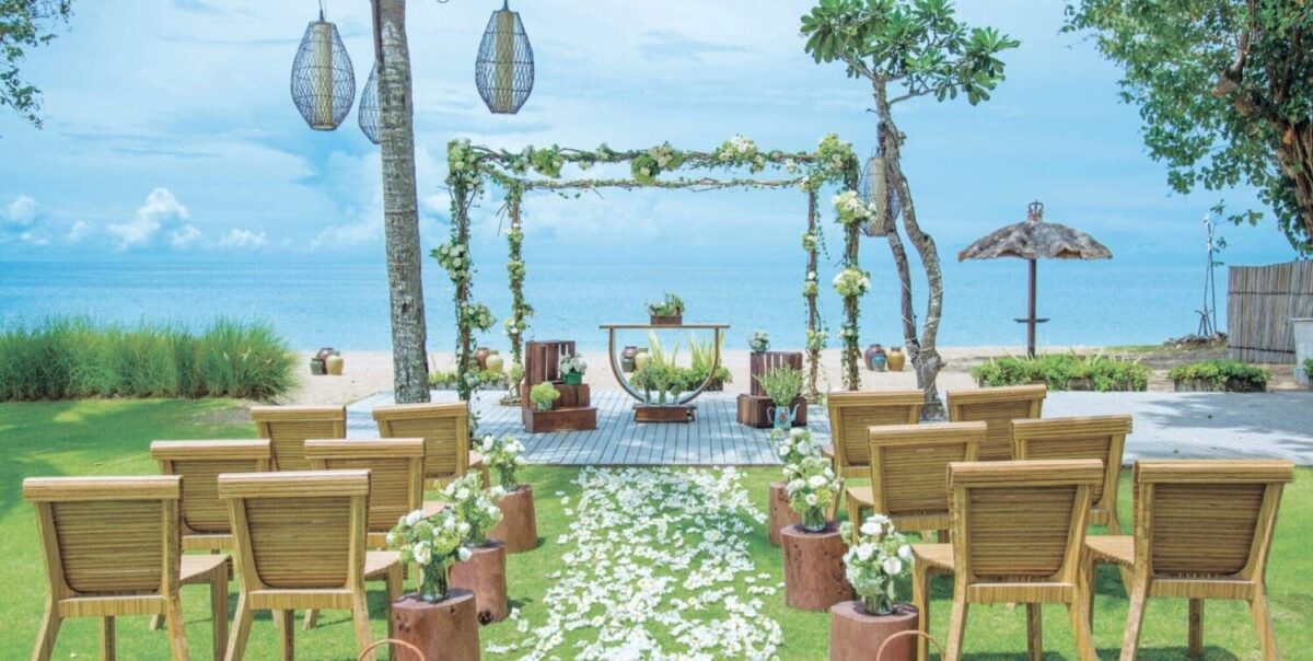 Beachfront wedding setup with floral arch and chairs