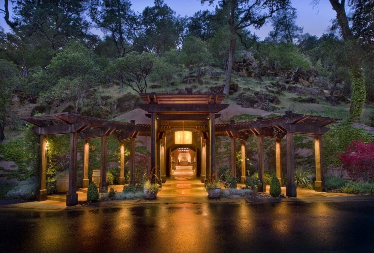 Illuminated resort entrance at dusk surrounded by lush trees