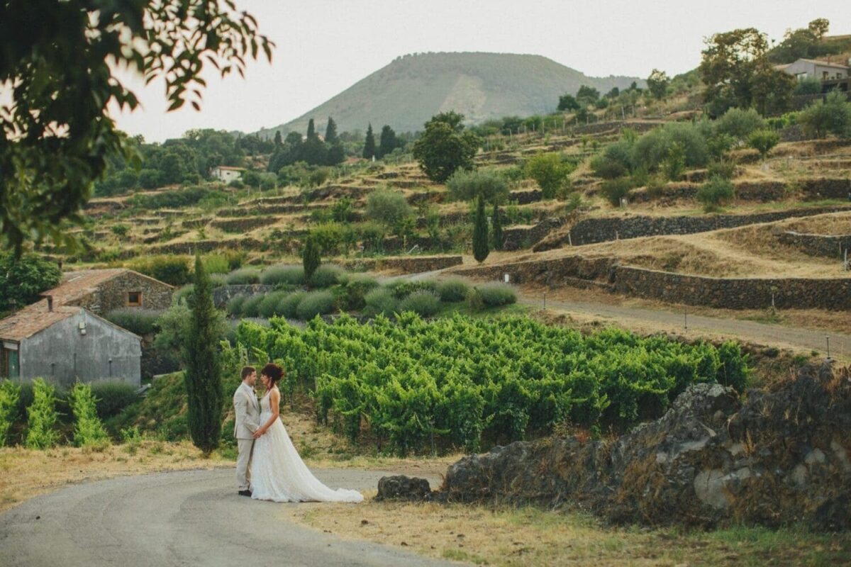 Bride and groom embrace on a countryside road with vineyards and hills