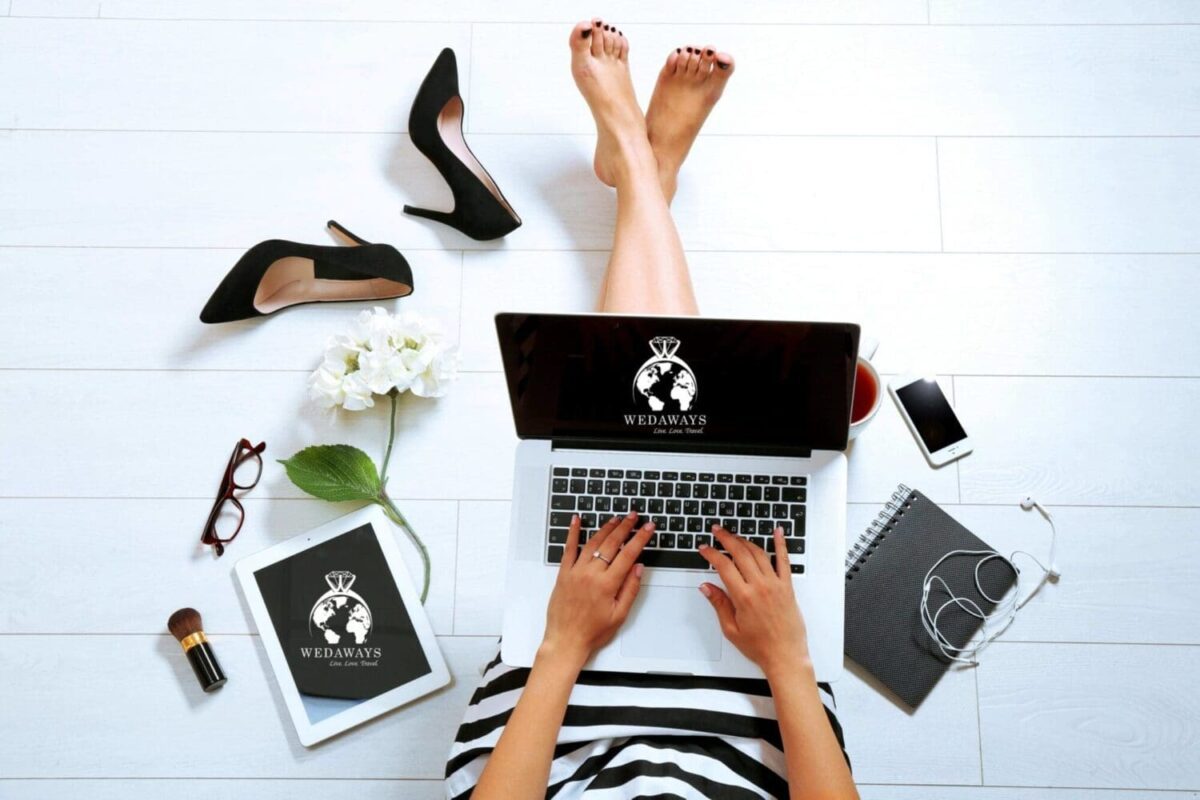 Woman planning destination wedding budget on laptop, surrounded by shoes and flowers