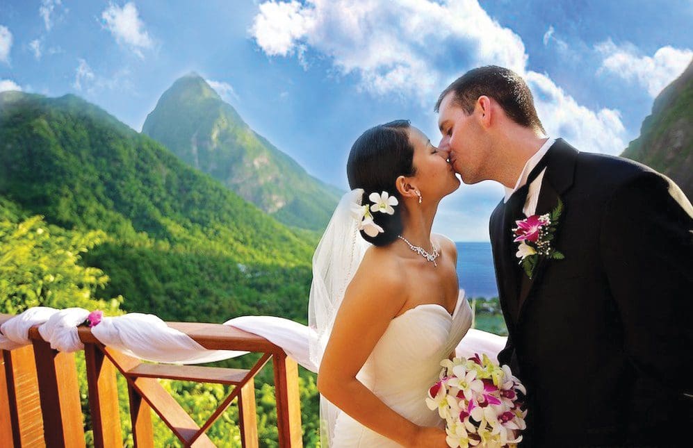 Bride and groom kissing in a breathtaking outdoor wedding with mountain backdrop