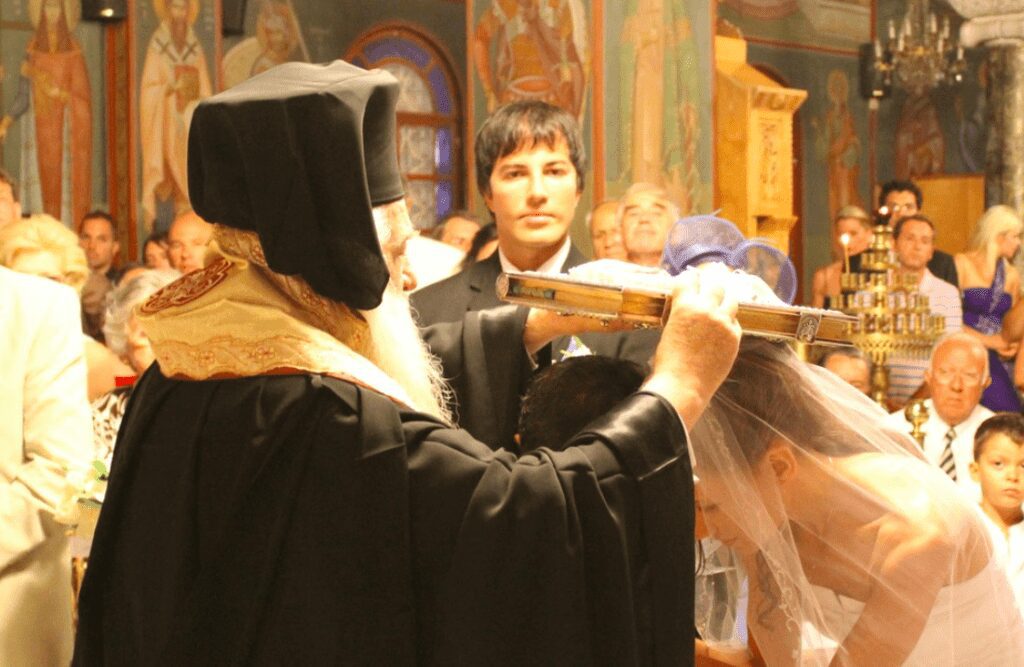 Greek Orthodox wedding ceremony with priest, groom, and bride