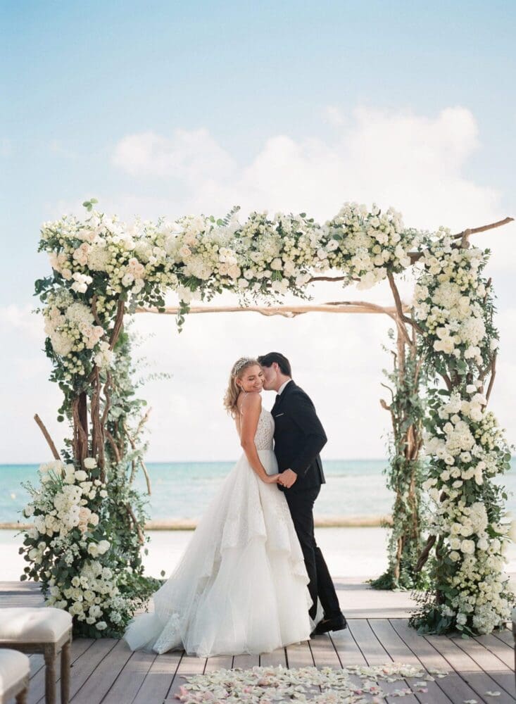 Elegant beach wedding under floral arch, perfect for luxury all-inclusive celebrations