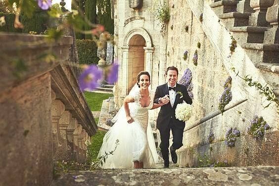 Bride and groom joyfully walking up stone steps at a romantic wedding venue