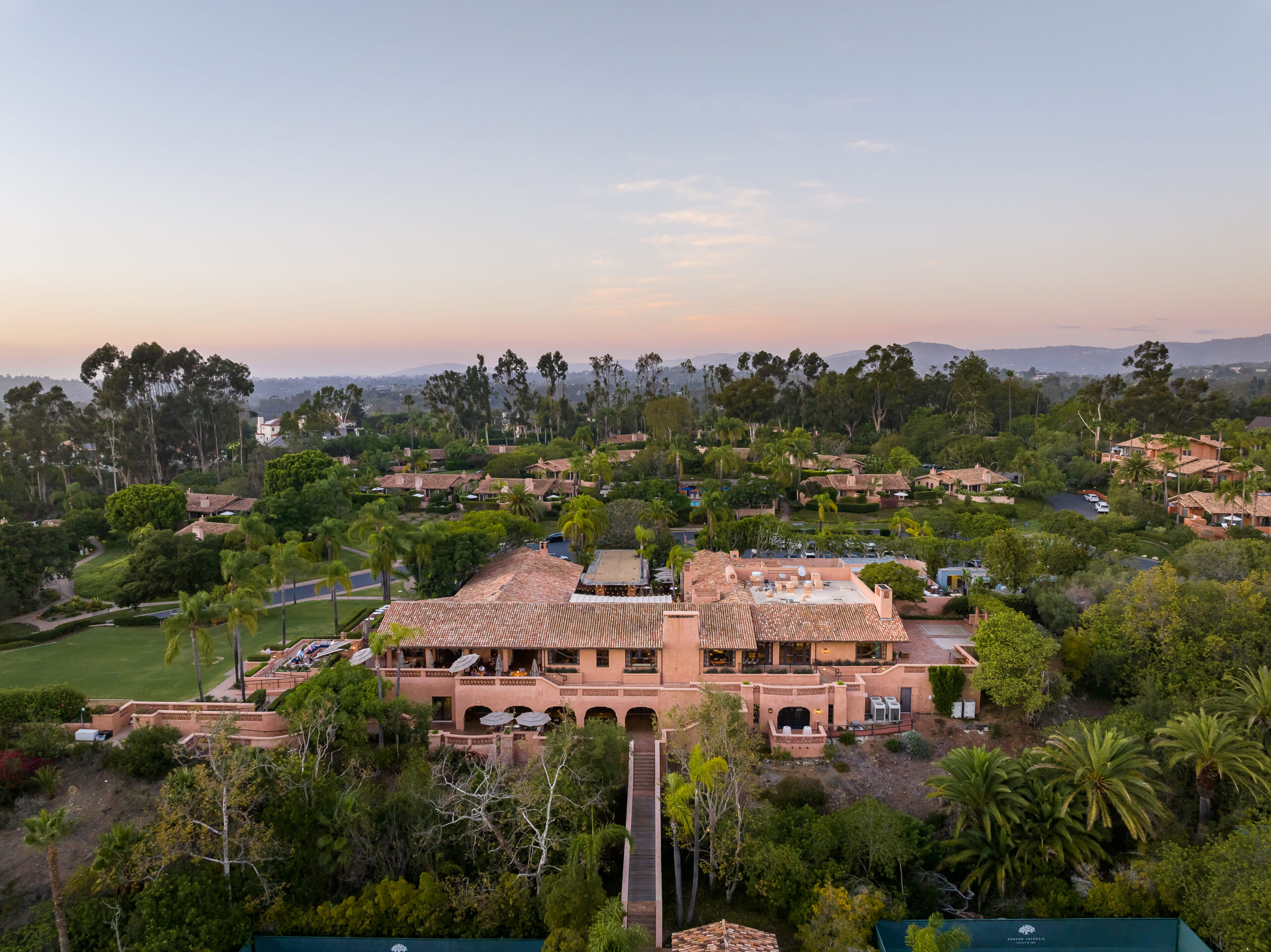 Aerial view of Rancho Valencia Resort & Spa surrounded by lush greenery at sunset