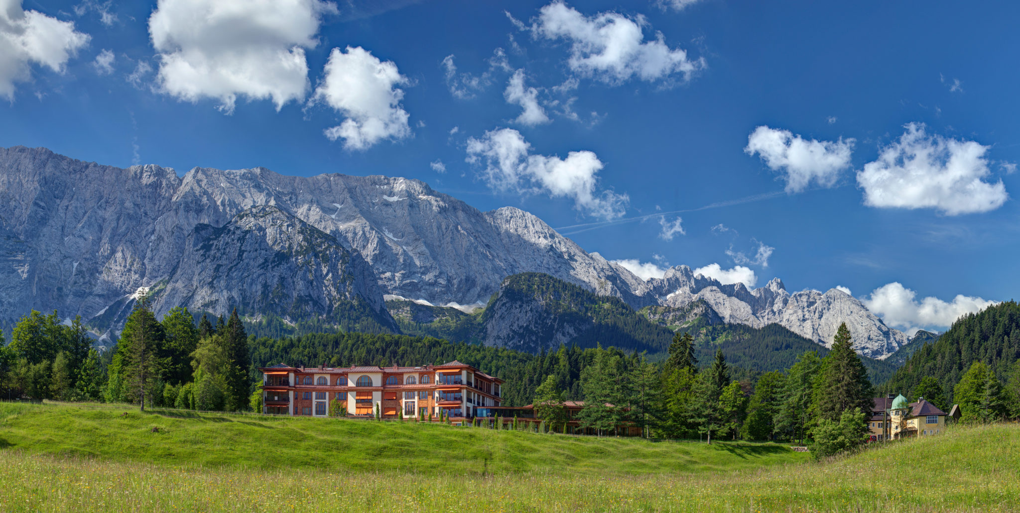 Schloss Elmau with mountain backdrop in Germany under a blue sky