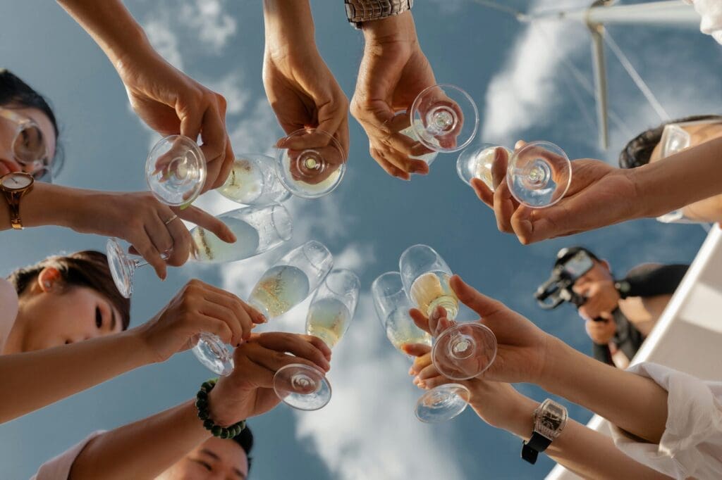 Guests raising champagne glasses against a blue sky at a destination wedding