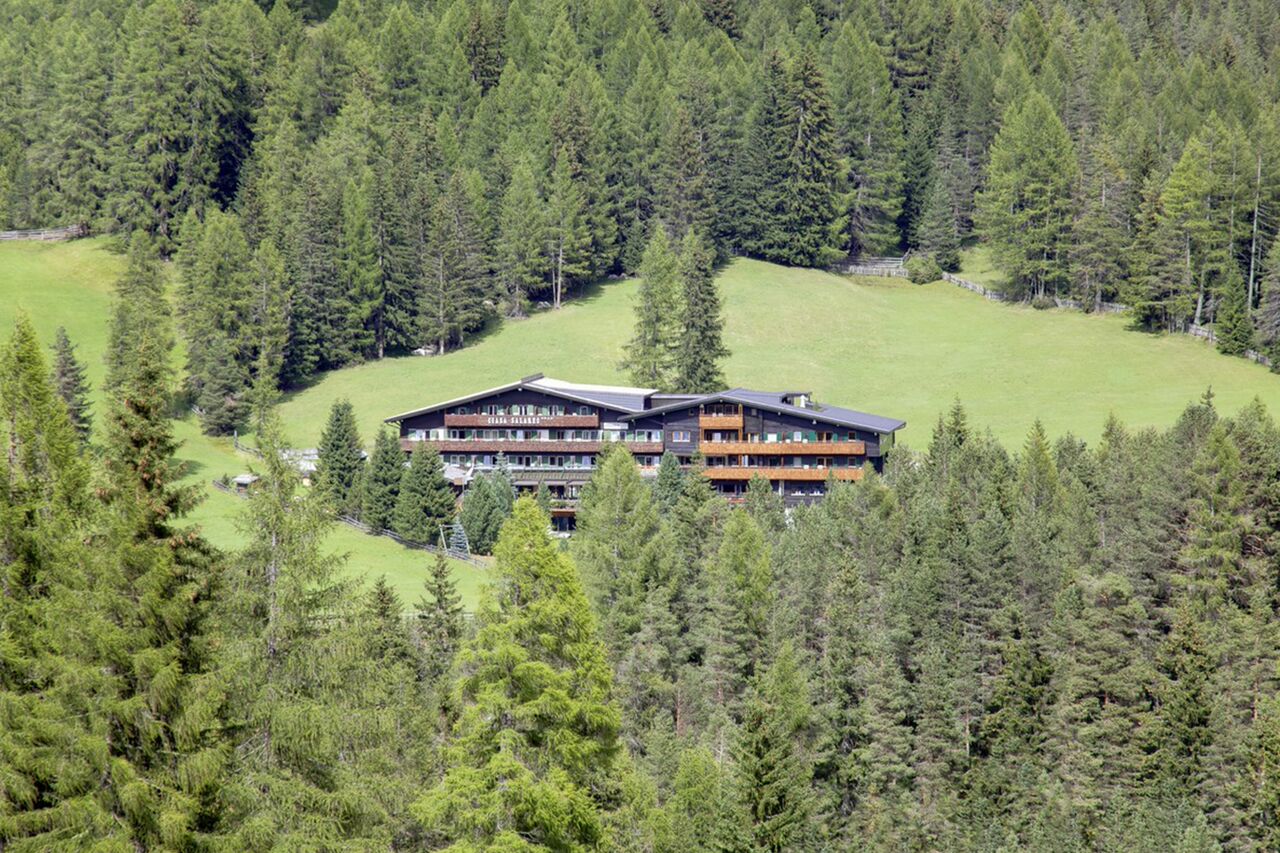Hotel Ciasa Salares surrounded by lush forest in Dolomites Italy