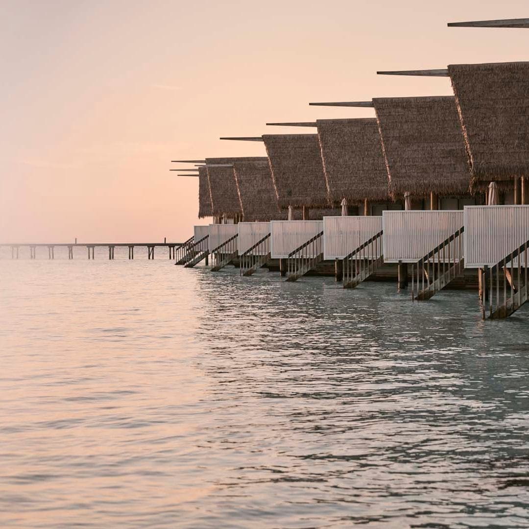 Overwater bungalows, perfect for honeymoon travel, at sunset