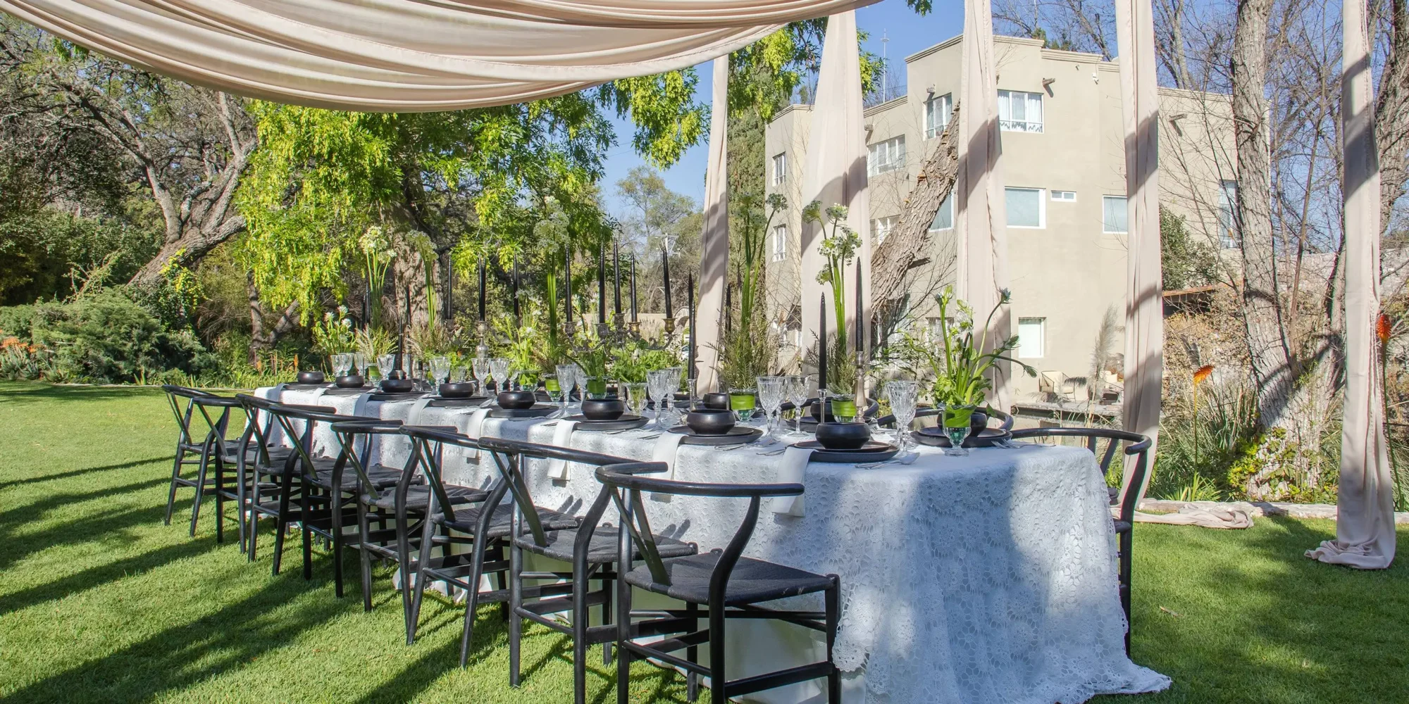 Elegant outdoor wedding reception table in Mexico, featuring black chairs and a lace tablecloth. Dream wedding setting.