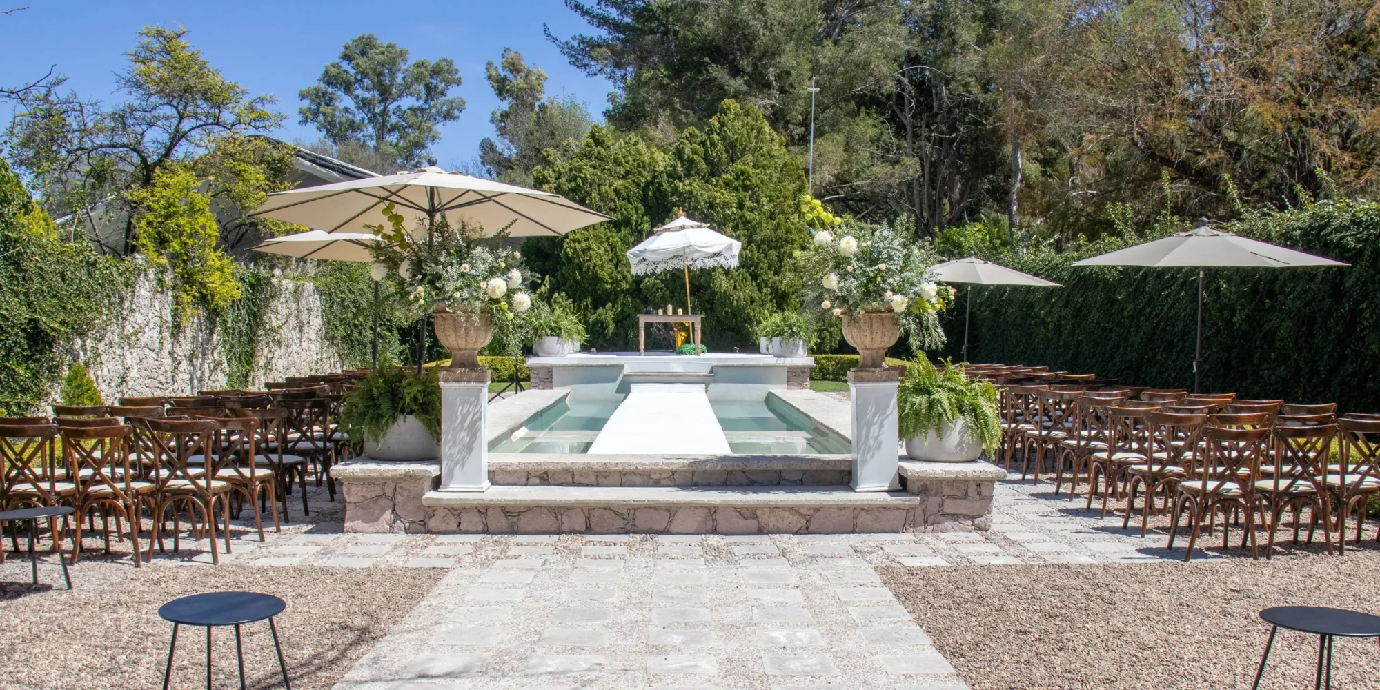 Outdoor wedding ceremony setup at Agua Bendita, Mexico. Rows of chairs face a poolside altar.