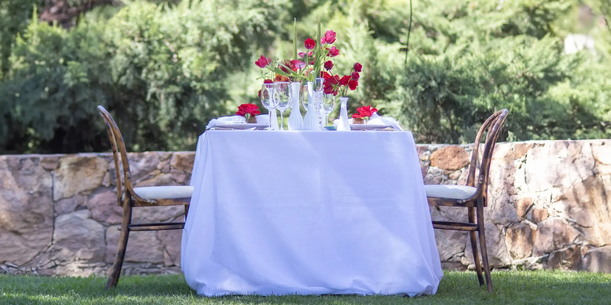 Romantic outdoor wedding table setting in Mexico with red flowers.