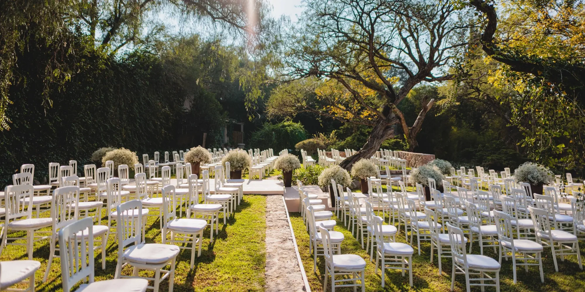 Rows of white chairs set up for a dream wedding ceremony in a lush Mexican garden.