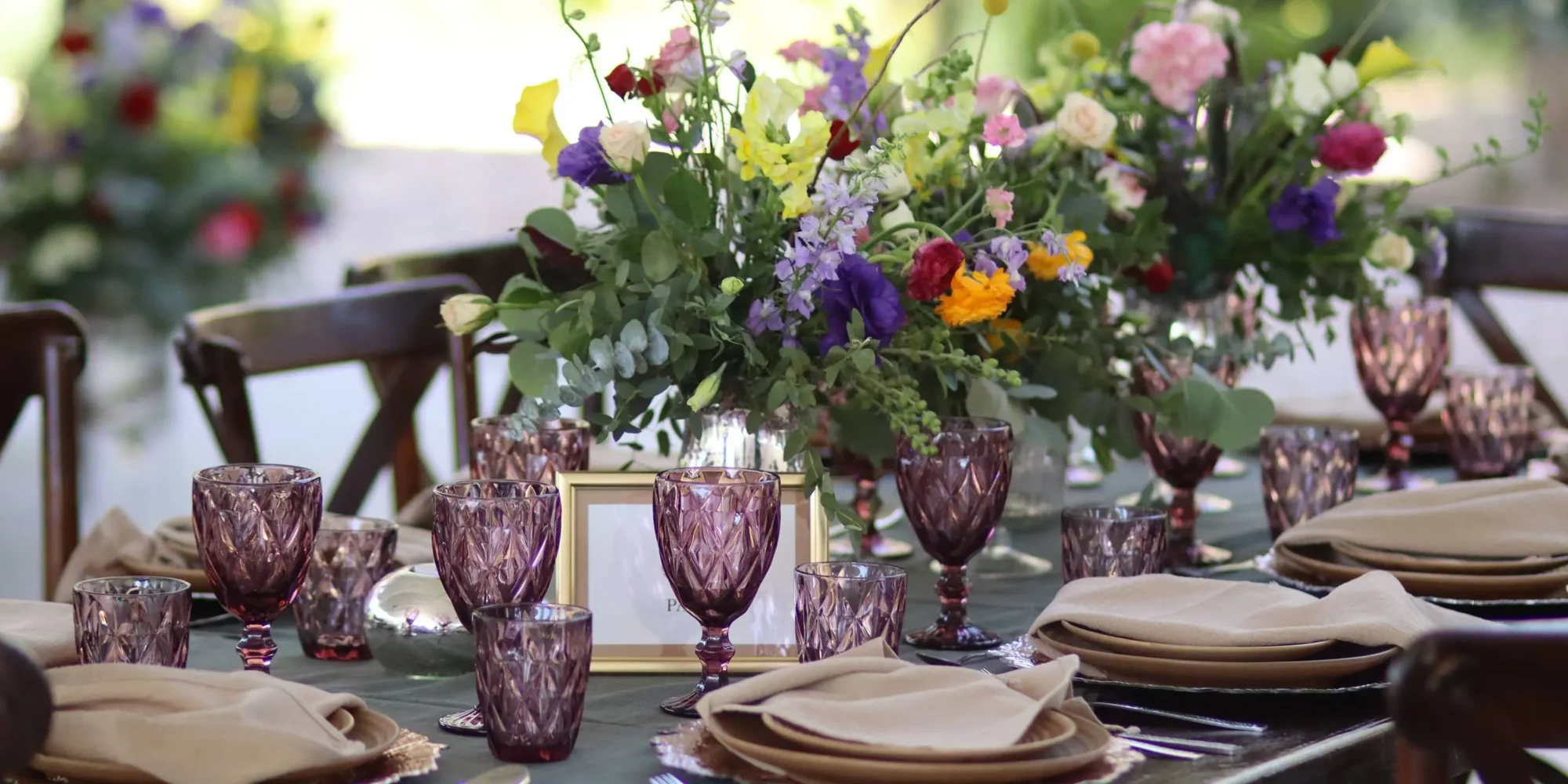 Elegant wedding table setting with purple glassware and colorful floral centerpiece. Dream wedding in Mexico.
