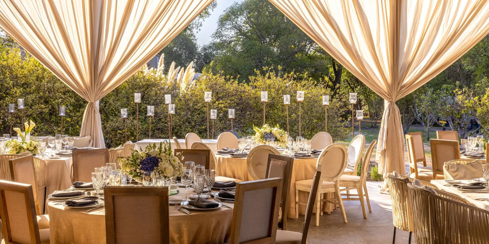 Elegant outdoor wedding reception in Mexico, featuring beige linens, wooden chairs, and candlelight. Dream wedding.
