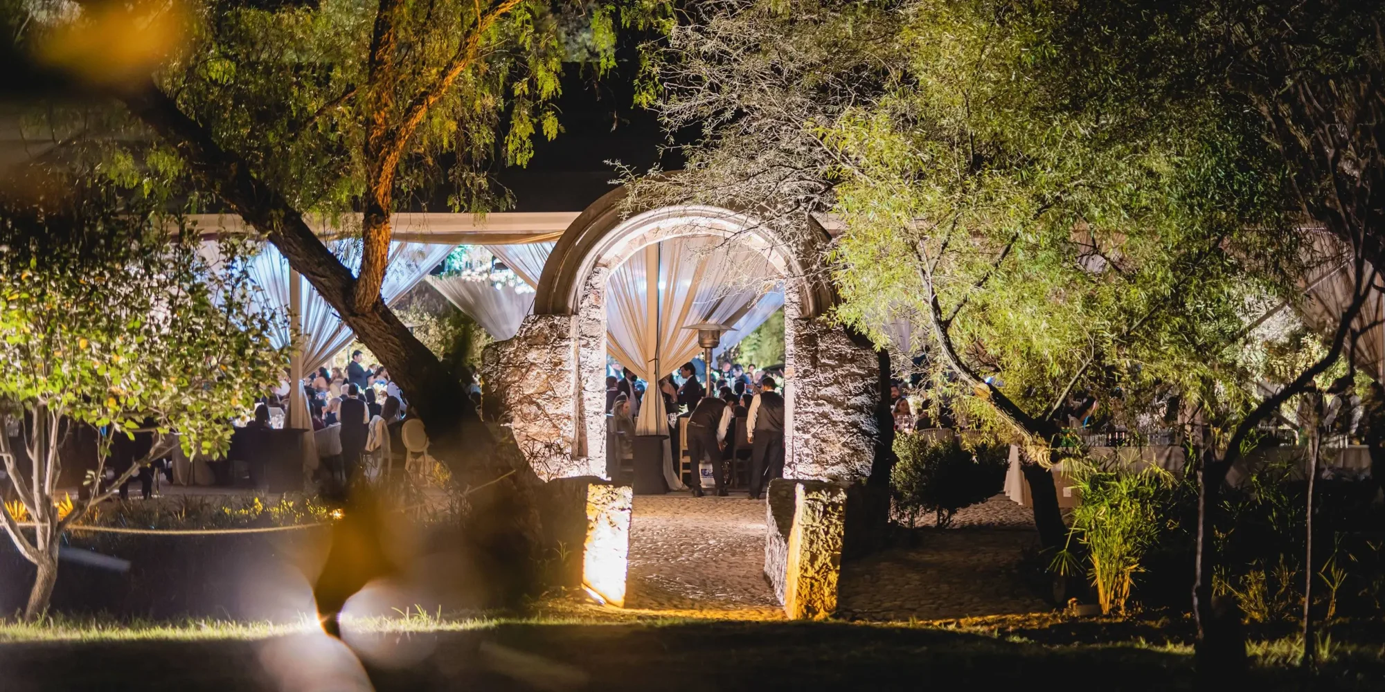 Romantic outdoor wedding reception at Agua Bendita, Mexico. Guests dine under twinkling lights.