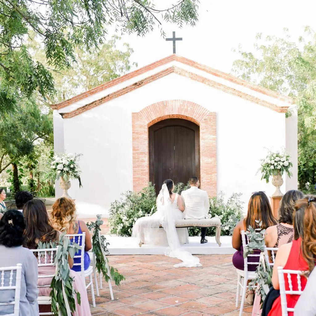 Bride and groom seated before a white chapel at a Dominican Republic wedding.