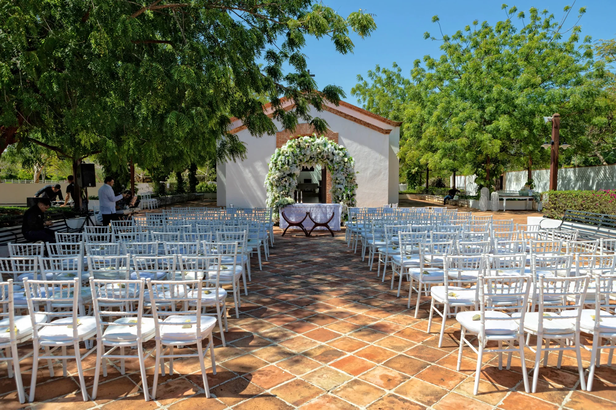Outdoor Dominican Republic wedding ceremony setup at Boutique Hotel Casa Hemingway. White chairs face a floral archway.