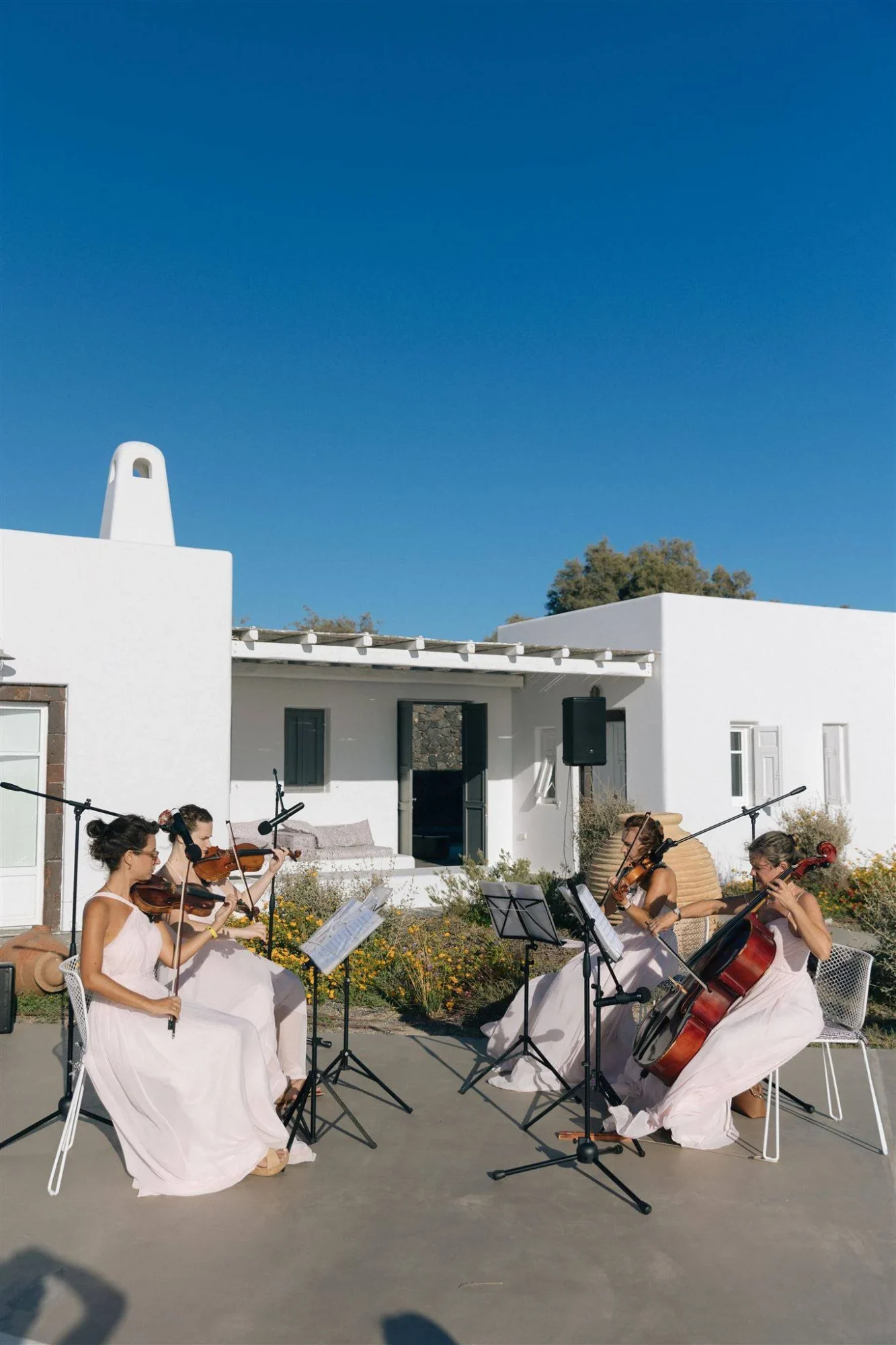String quartet in pink dresses performs at a Santorini wedding. Dream wedding in Santorini.