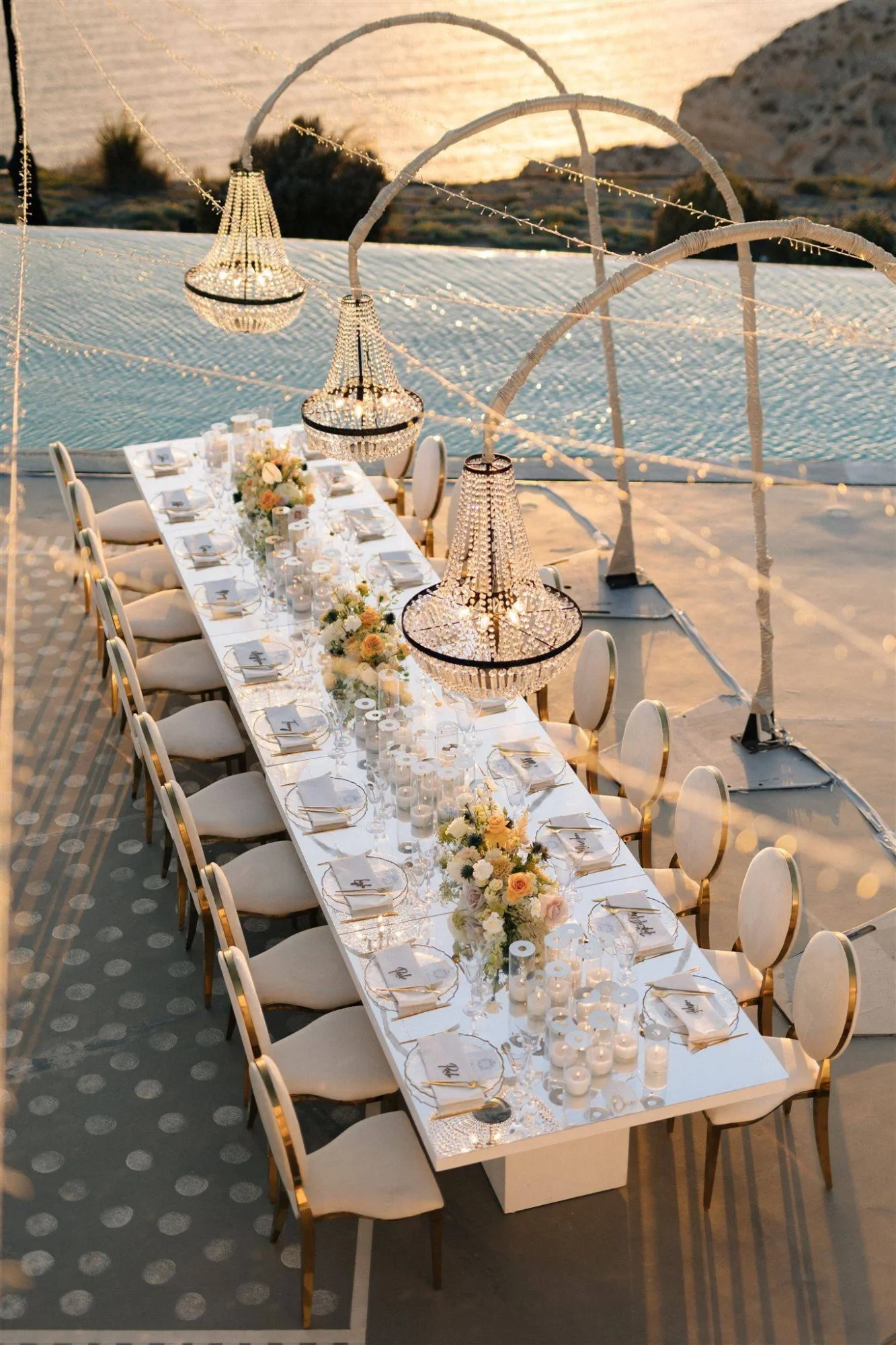 Elegant Santorini wedding reception table setting with crystal chandeliers and ocean view.