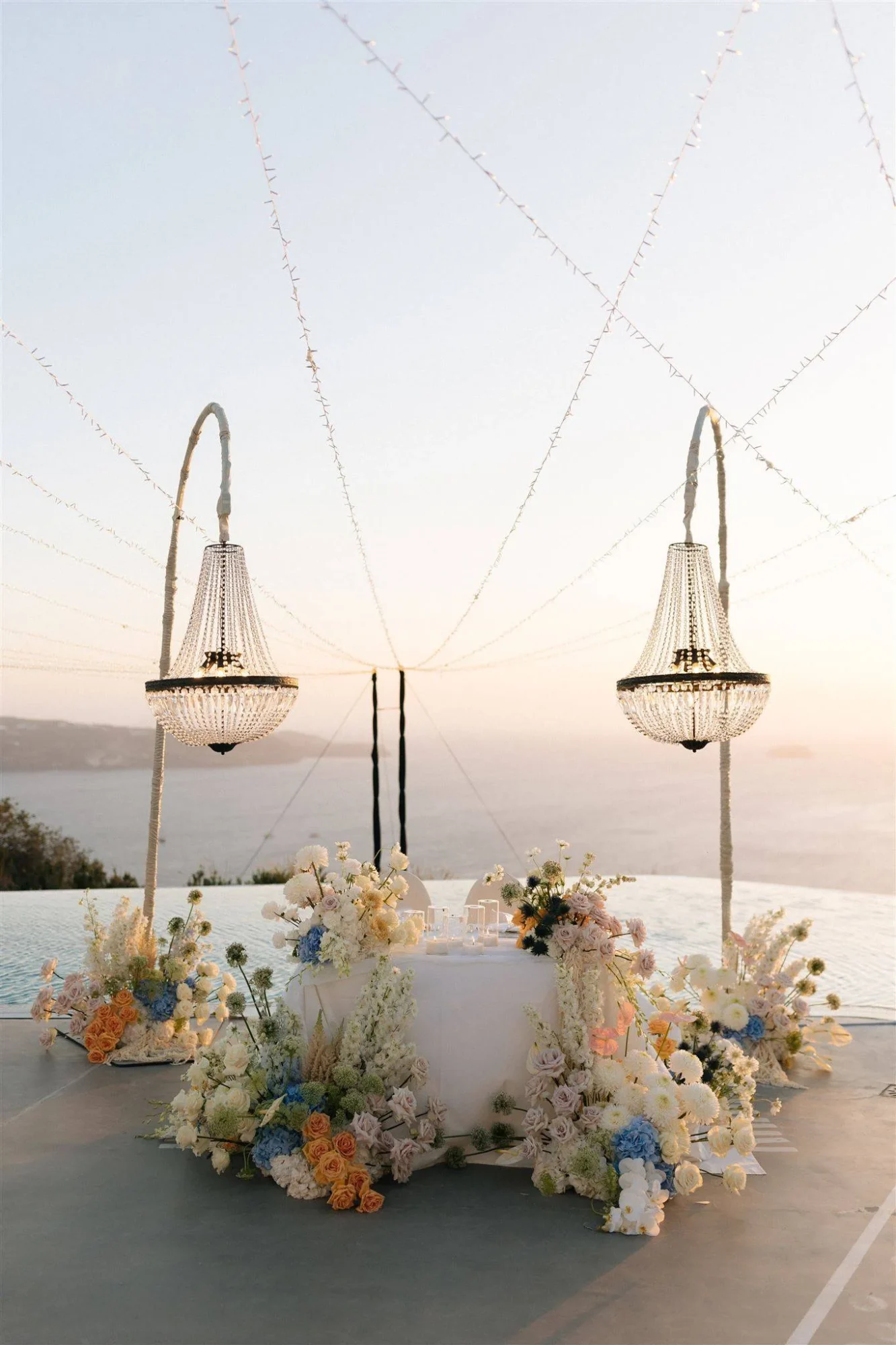 Romantic Santorini wedding reception with crystal chandeliers and floral arrangements.