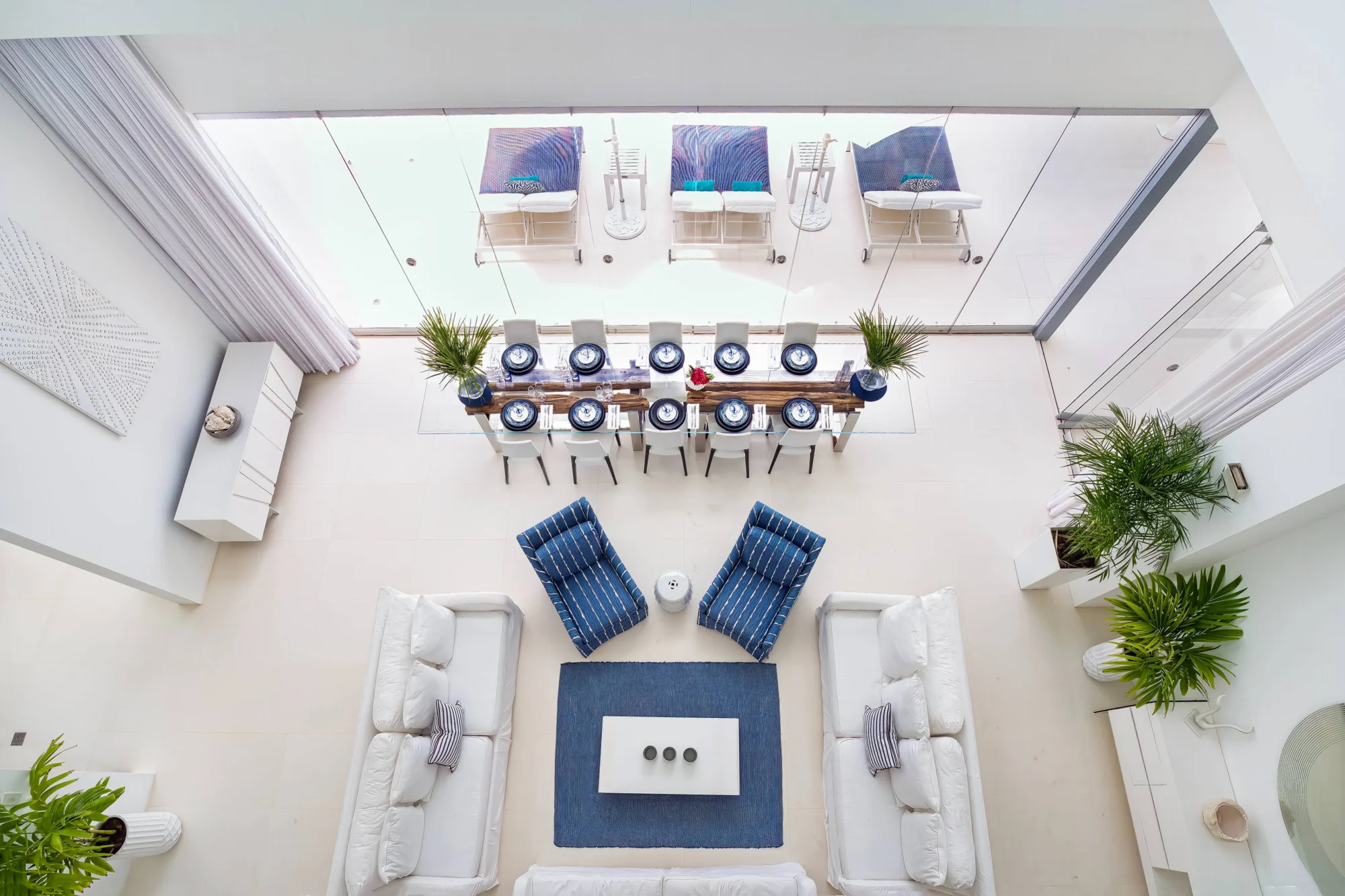 Luxury Anguilla beach house interior: white sofas, dining table, and ocean view.